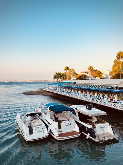 During the day there are white and blue boat on the wharf
